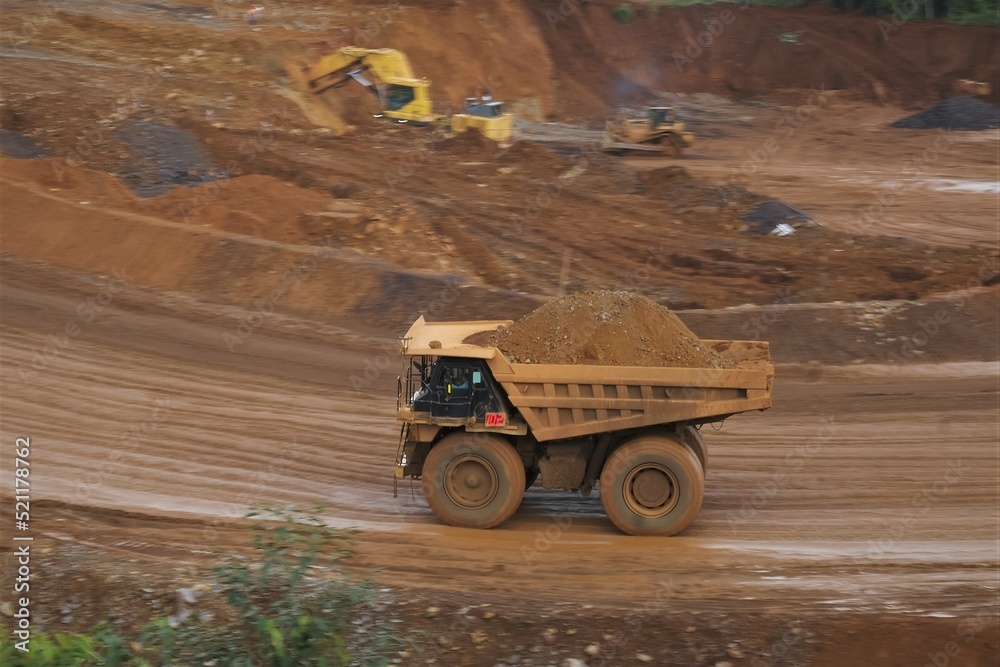 Obraz premium A haul truck is transporting material at a nickel mine site. Rigid dump trucks specifically engineered for use in high-production mining and heavy-duty construction environments.