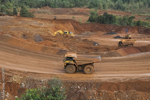 A haul truck is transporting material at a nickel mine site. Rigid dump trucks specifically engineered for use in high-production mining and heavy-duty construction environments.