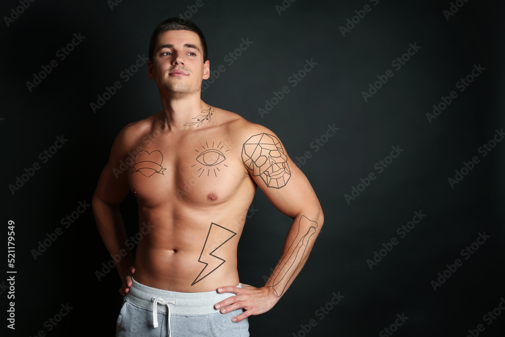Naklejka premium Handsome man with beautiful tattoo sketches on black background. Space for text