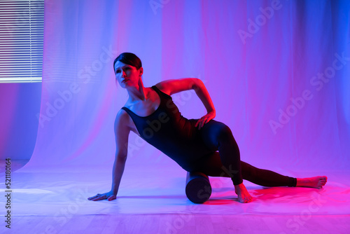 Fototapeta Naklejka Na Ścianę i Meble -  Athletic woman in high school, swimsuit and leggings, doing yoga, push-ups or push-ups, falancasana, plank pose variation, beautiful girl exercising at home or in a yoga studio