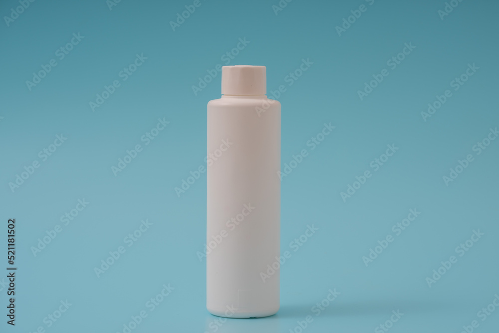 White plastic bottle with a green cap on a blue background White plastic bottle with a green cap on a blue background