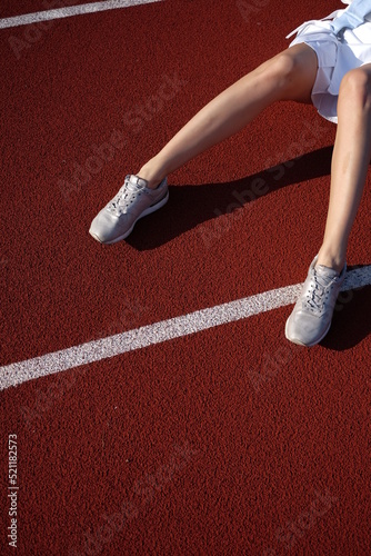 female legs in sneakers on the sports ground