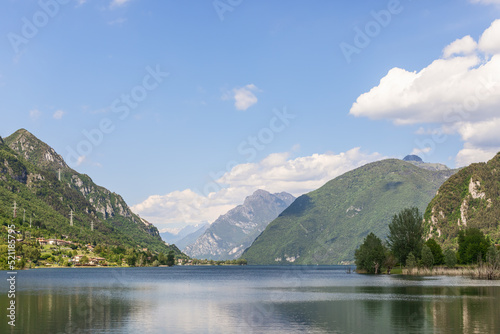 Light summer haze from evaporation over the waters of an alpine lake Idro(Lago d'Idro) surrounded by high rocky wooded mountains. Brescia, Lombardy, Italy © Artem