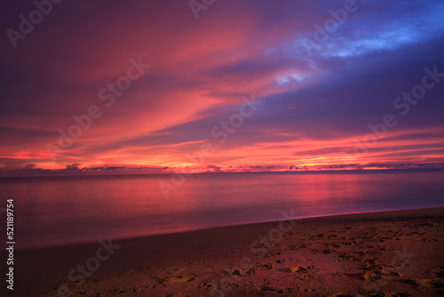 Beautiful sunset above sea or ocean. Vibrant and soft colors, magic light.  reflection of sun in the water and sand on beach. Concept of romantic time on vacation in tropical.