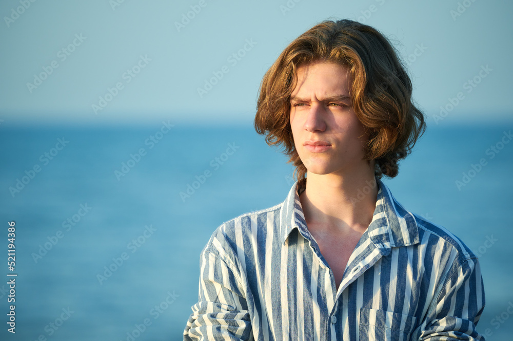 Portrait of serious young teenager boy at sea sunset Portrait of serious young teenager boy at sea sunset