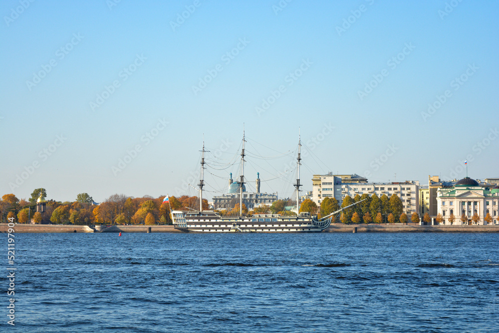 the old ship in the autumn on the blue river with yellow trees on the background