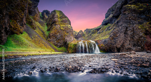 Wonderful nature of Iceland. fresh green grass and icelandic moss near river with waterfall. Tipical Icelandic scenery during sunset. Dramatic Scene of Stjornarfoss Waterfall with colorful sky