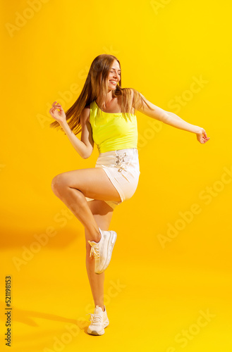 Cheerful young girl, student dancing isolated on bright yellow background. Concept of beauty, art, fashion, emotions and facial expressions