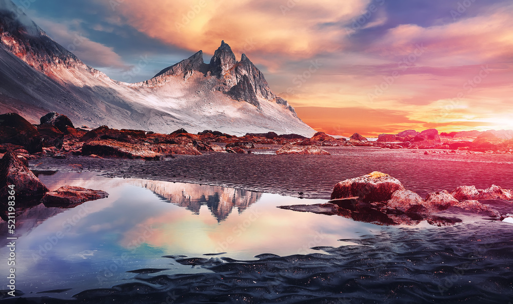 Fantastic colorful seascape of Iceland. Dramatic view on magic rocky mount and perfect reflection. with clouds during sunset. Amazing nature landscape near Stokksnes cape and Vestrahorn Mountain.