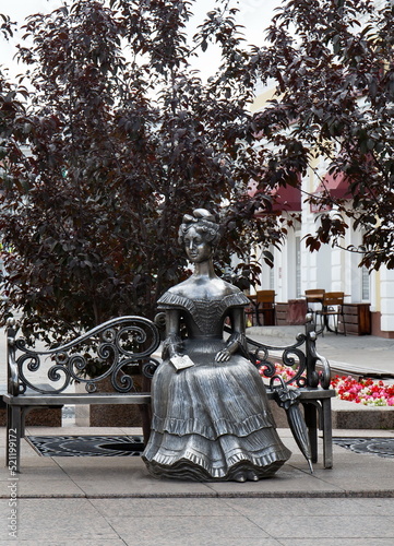Konstfotografi Silver sculpture of a beautiful young lady on a bench in the historical center o