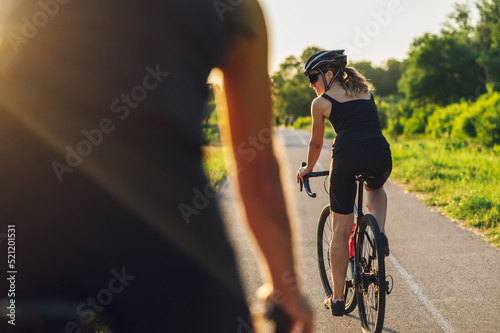 Fototapeta Naklejka Na Ścianę i Meble -  Couple riding road bicycles outside and wearing helmets and sunglasses