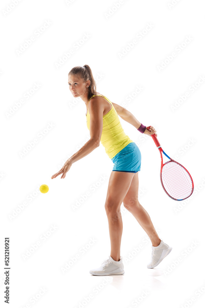 Portrait of young woman, professional tennis player training, serving ball isolated over white studio background