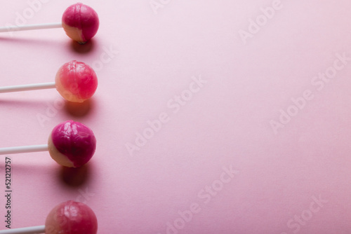 Overhead view of lollipops arranged side by side with copy space against pink background photo