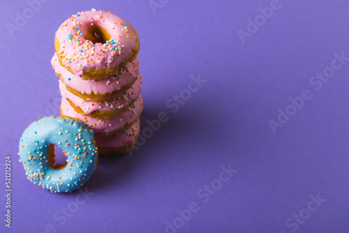 High angle view of fresh donuts with sprinklers by copy space against purple background