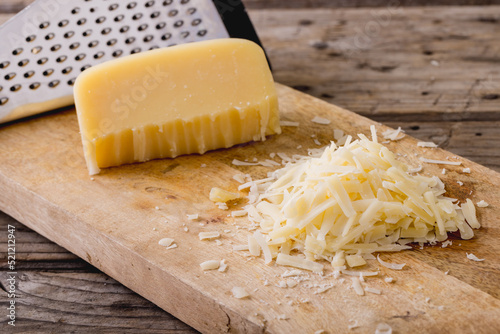 Close-up of grated cheese with grater on wooden board, copy space