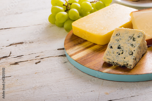 Close-up of various cheese with grapes on table, copy space