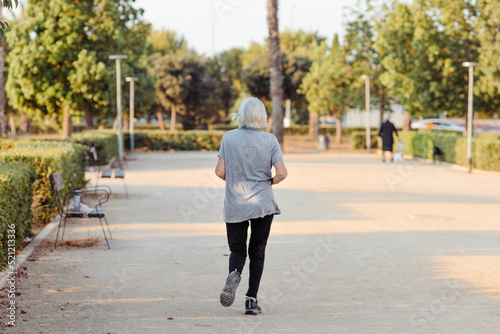 older woman running in a park with her back to the camera
