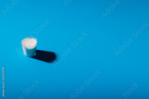 High angle view of milk glass on blue background with copy space