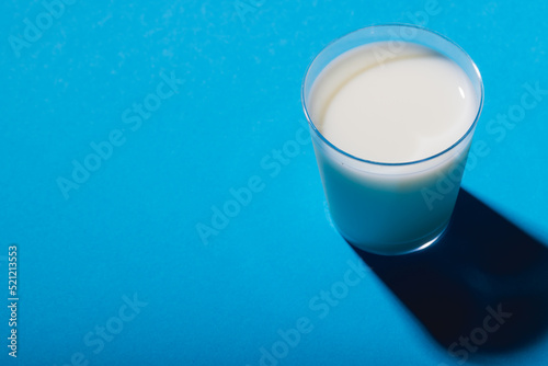 High angle view of glass of milk on blue background with copy space