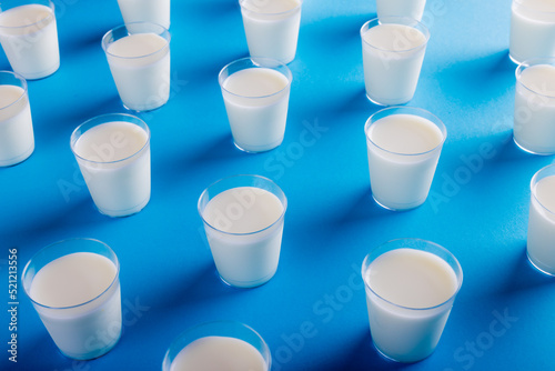 Milk glasses arranged on blue background, copy space