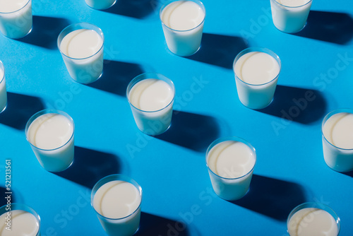 High angle view of milk glasses arranged on blue background, copy space