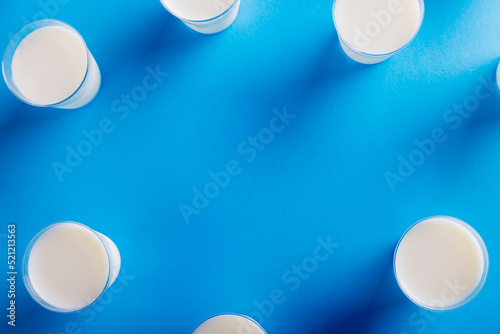 Overhead view of milk glasses arranged on blue background, copy space