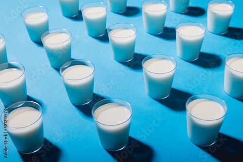 High angle view of milk glasses arranged over blue background, copy space