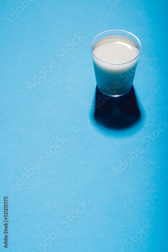 High angle view of glass of milk on blue background, copy space