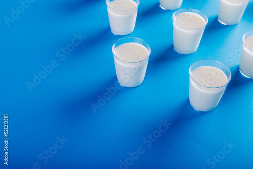 High angle view of milk glasses arranged on blue background with copy space