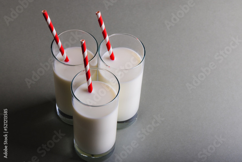High angle view of milk in glasses with straws on gray background, copy space