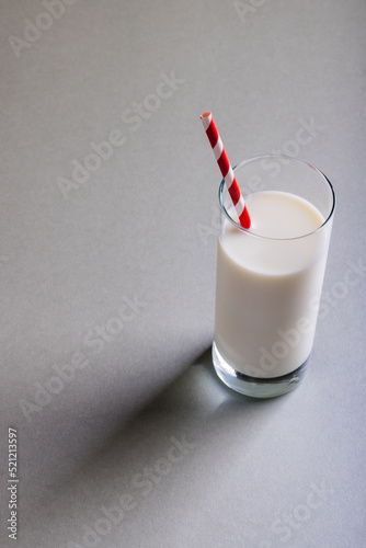 High angle view of milk in glass with straw on gray background, copy space