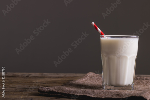 Milk in glass with straw on table against gray background, copy space