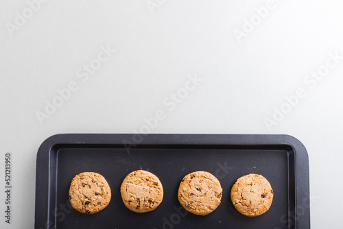 Directly above view of fresh cookies arranged in tray on white background, copy space