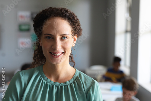 Close-up portrait of smiling young female teacher in classroom