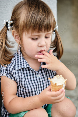 Little baby girl eating ice cream  licking her fingers