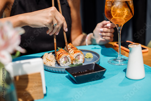 Customer of the restaurant is eating a sushi rolls. Close up