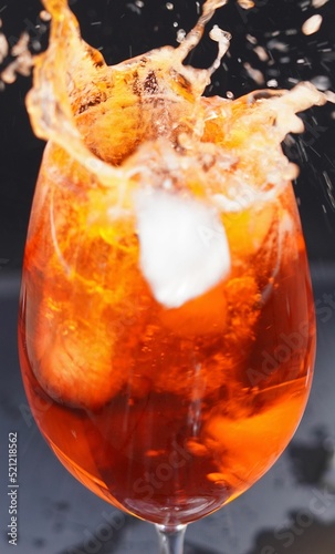 Fotografia, Obraz Vertical closeup of a glass filled with splashing Spritz Veneziano, an Italian c