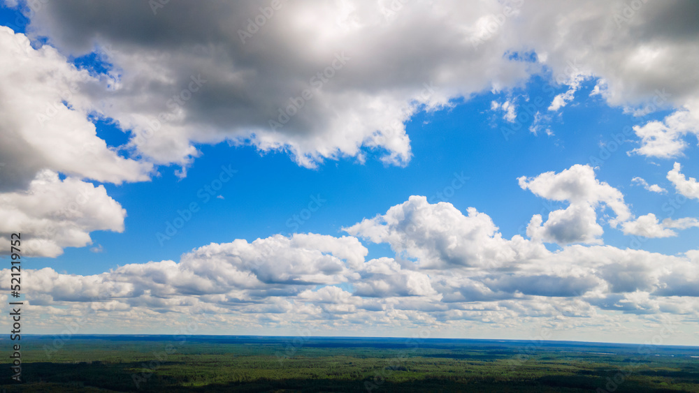 Blue sky panorama with clouds over tops of green trees. Blue sky and white cloud soft. White clouds background. Blue sky panorama with clouds over tops of green trees. Blue sky and white cloud soft. White clouds background.
