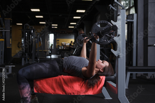 Female bodybuilder doing bench press exercise at gym