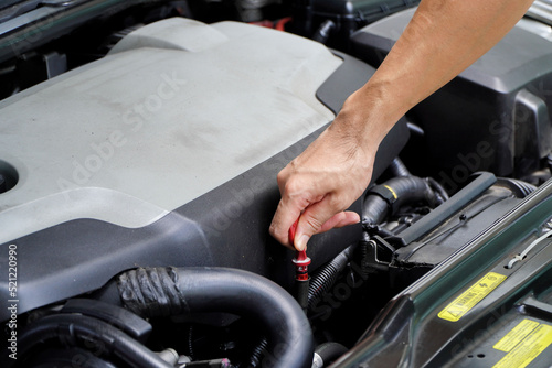 Auto mechanic checking the oil level in car engine,inspects engine water level dipstick,concept of checking the engine oil level every time before leaving.