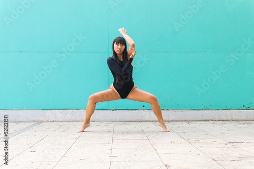 Asian ballerina doing plie squat on street photo