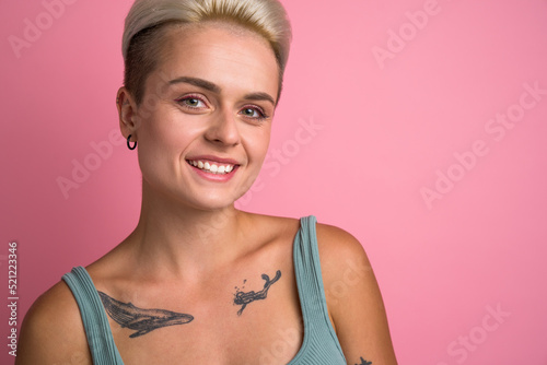 Short haired blonde woman with tattoos looking straight to the camera
