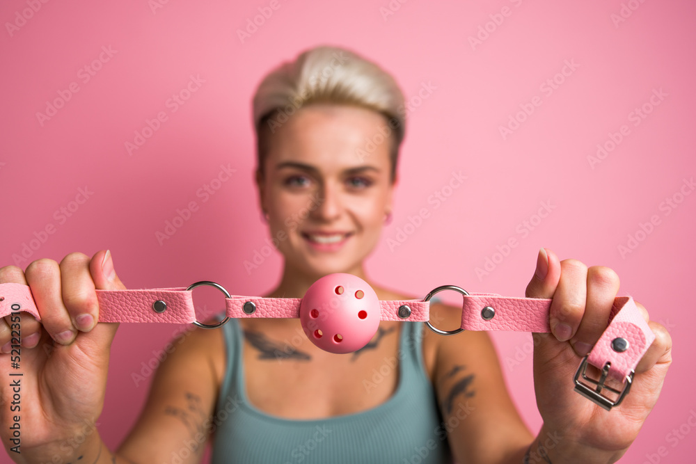 Alluring girl playing pervert fetish game and preparing closing mouth with pink gag - obrazy, fototapety, plakaty 