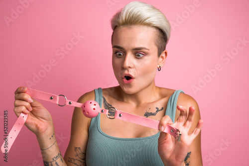 Sexy girl looking with surprised face at pink gag while preparing playing pervert fetish game