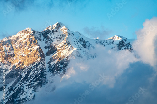 Beautiful sunset in the  snow covered mountains and fog  blue sky with  clouds.