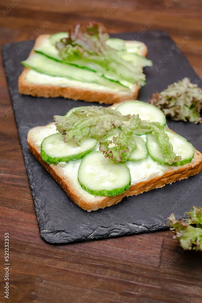 Bruschetta sandwich bread toast with soft green avocado cheese ricotta,fresh cucumbers,basil greenery on wooden cutting board.Tasty healthy vegetarian food,Italian cuisine appetizer.top view flat lay Bruschetta sandwich bread toast with soft green avocado cheese ricotta,fresh cucumbers,basil greenery on wooden cutting board.Tasty healthy vegetarian food,Italian cuisine appetizer.top view flat lay