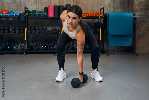 Active muscular woman having cross workout training with dumbbells weights in the gym