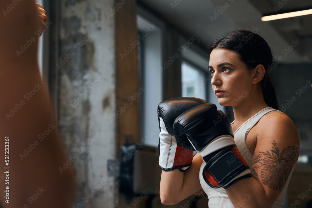 Serious young woman wearing special gloves training on the heavy bag the jab