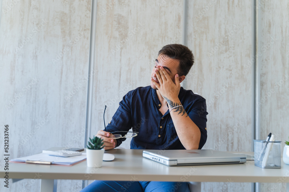 A man is stretching and holding his neck because of neck and back pain from long sitting on his chair while working in his home office during the day A man is stretching and holding his neck because of neck and back pain from long sitting on his chair while working in his home office during the day