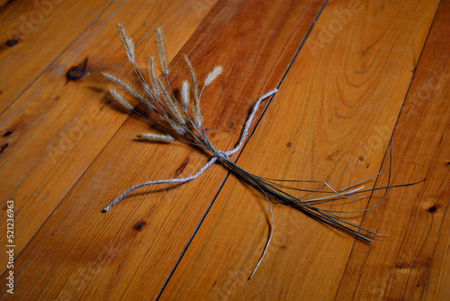 A posy or small bouquet of Australian native grass flowers photographed laying on a polished timber floor